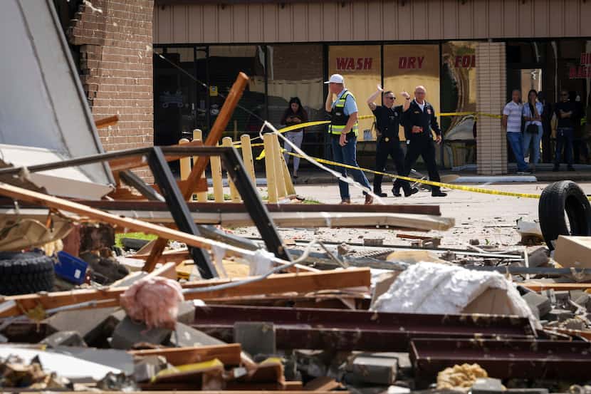 Authorities work at the scene where a tornado damaged several businesses Wednesday, April...