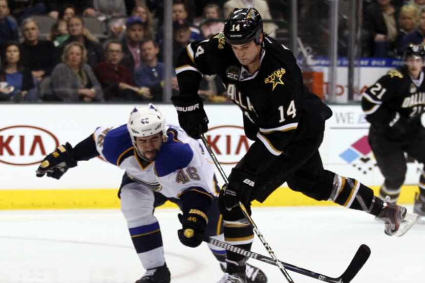 Dallas' Jamie Benn takes a shot as St. Louis' Roman Polak tries to take it during a game...