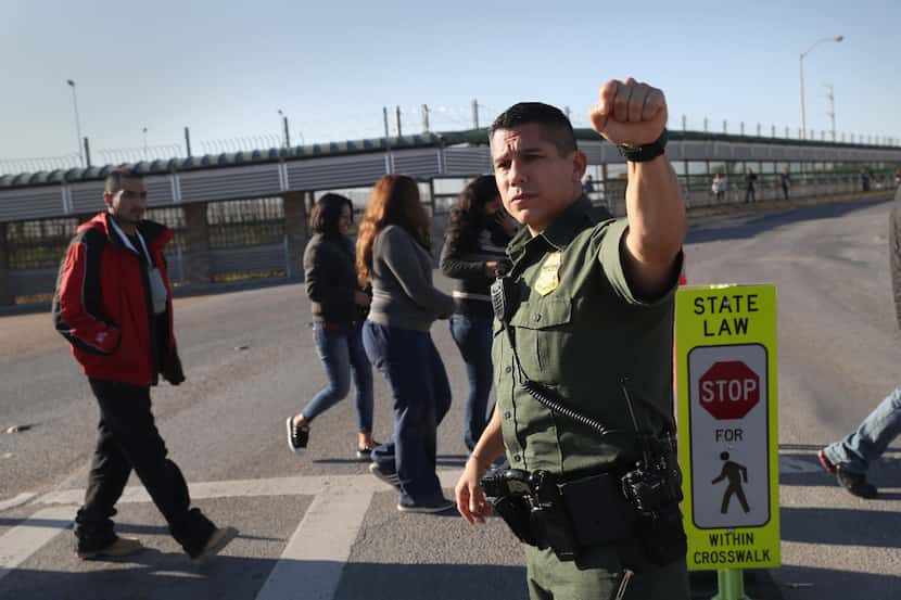 A U.S. Border Patrol agent stops traffic as immigrants are deported across an international...