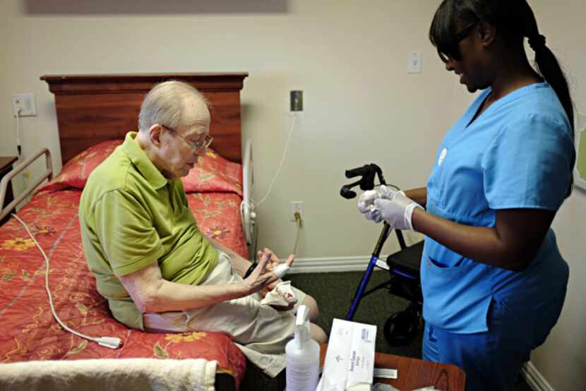 Trakista Wilkerson (right), a nurse at The Plaza at Edgemere, helps bandage a small cut for...