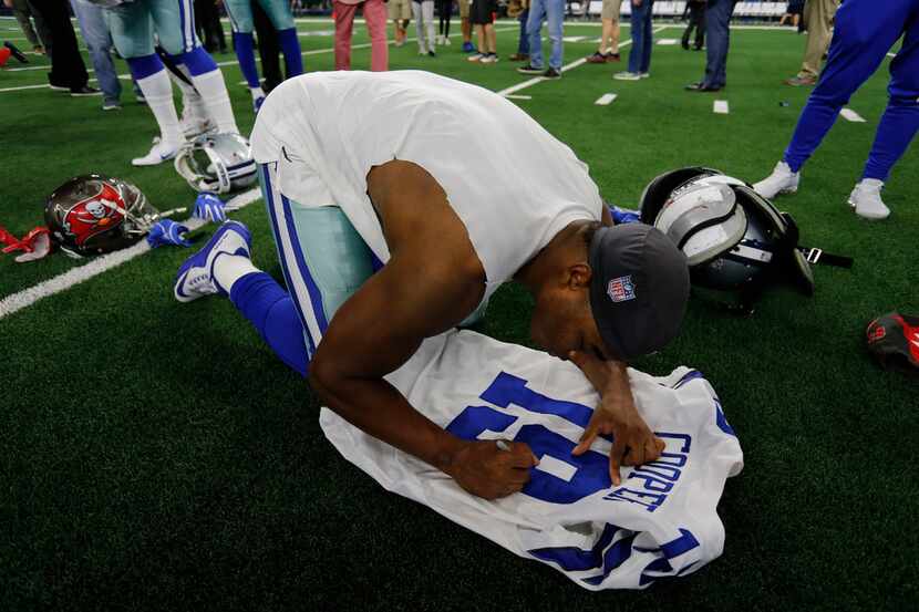 Dallas Cowboys wide receiver Amari Cooper (19) signs his jersey for a Tampa player after the...
