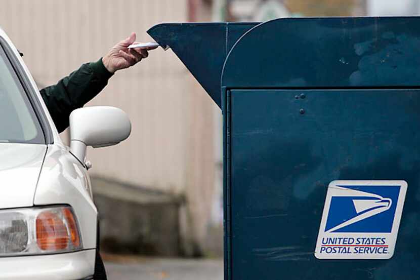 File photo of a customer dropping mail into a mailbox.