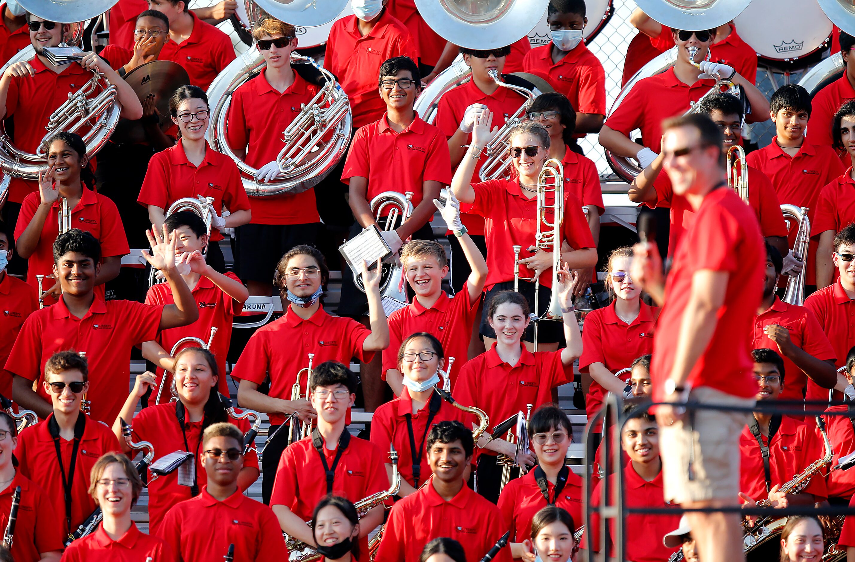 The Liberty High School band acknowledges an administrator on the field before kickoff as...