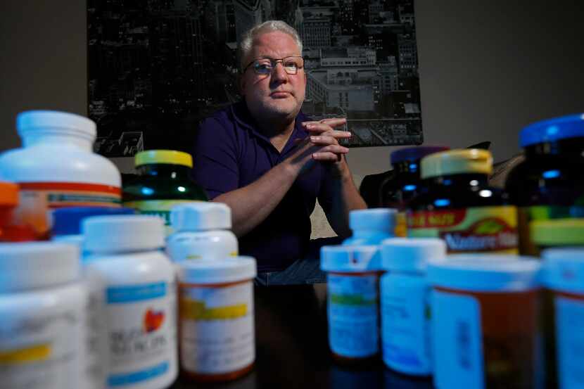 Dave Newman poses for a photograph with medicines and nutritional supplements he takes daily...