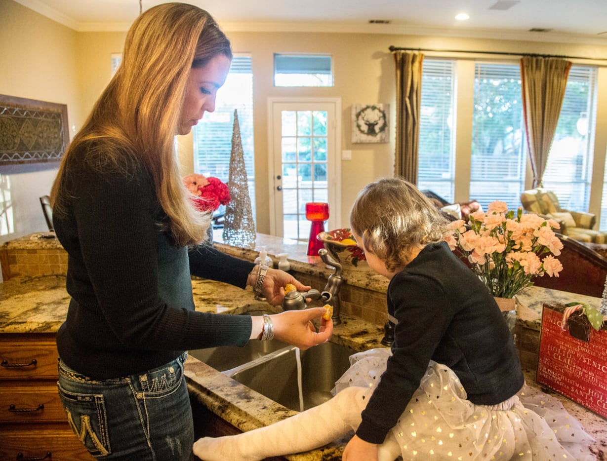 Meredith Greenstreet feeds her daughter Alexis, 3, an orange at their home in Flower Mound...