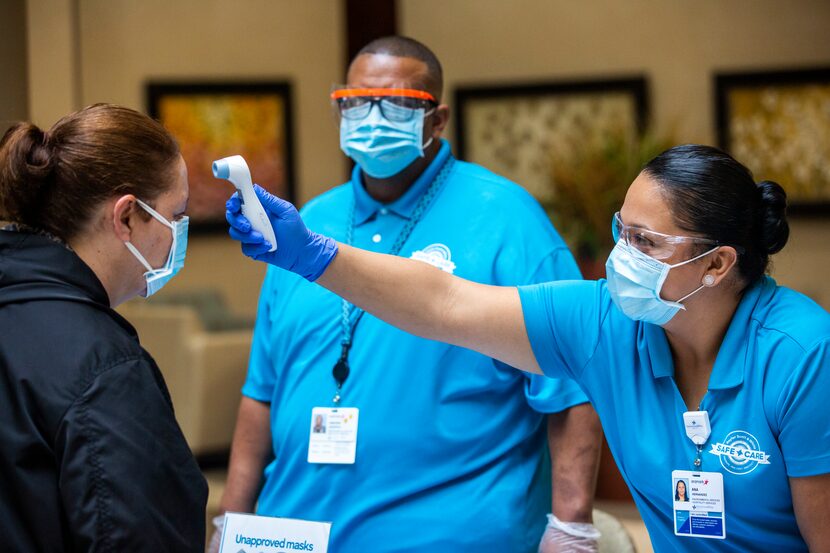 Ana Hernandez and Vincent Hargrove record the temperature of Maria Ruiz at a COVID-19...