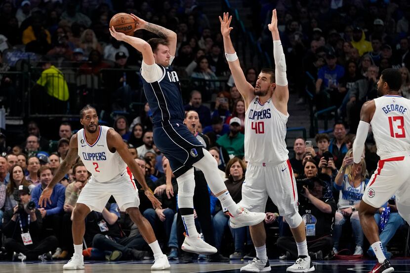 Dallas Mavericks guard Luka Doncic jumps to pass against Los Angeles Clippers defenders...