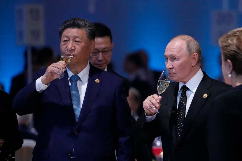 Russian President Vladimir Putin and Chinese President Xi Jinping hold glasses during a...