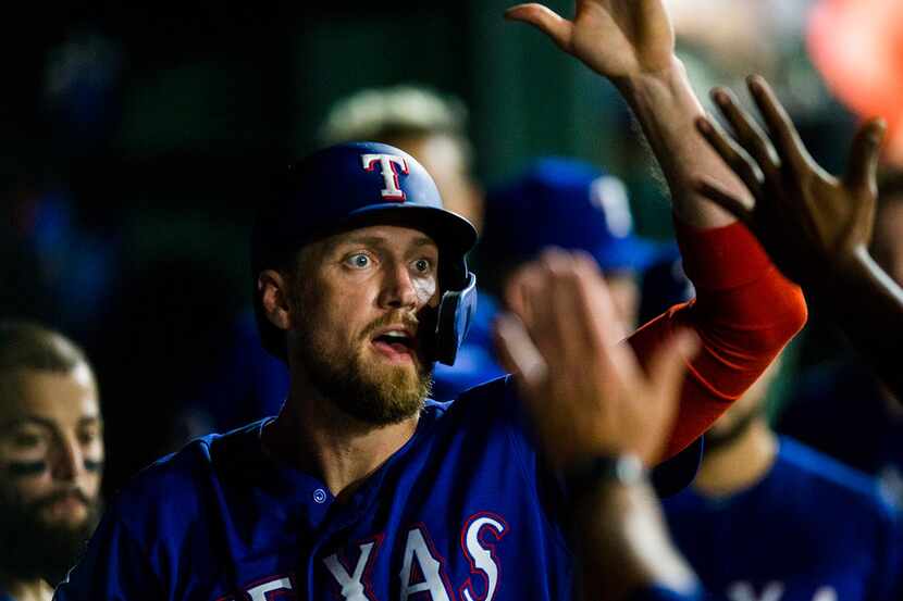 The Texas Rangers' Hunter Pence celebrates a run in the dugout during the sixth inning...