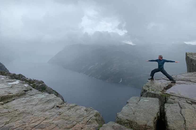 Dallas native Don Wilks practices a yoga warrior pose on the Preikestolen cliff in Norway....