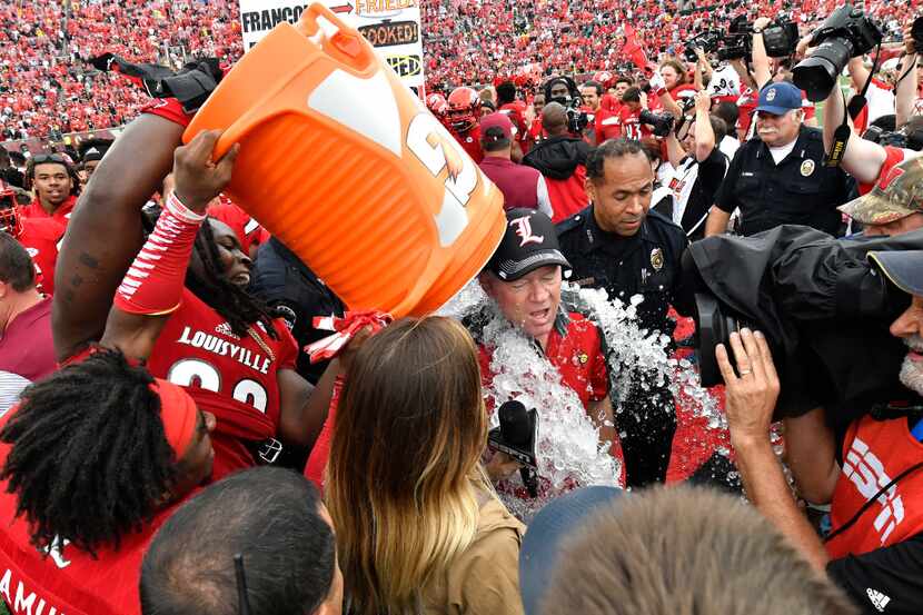 Louisville head coach Bobby Petrino's players doused him after Louisville's 63-20 victory...