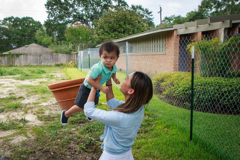 Cathy Pham plays with son Aidan at the site where their home once stood in southwest...