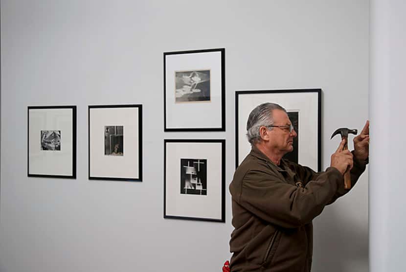  Gallery owner Burt Finger affixes a nail while hanging work at Photographs Do Not Bend...
