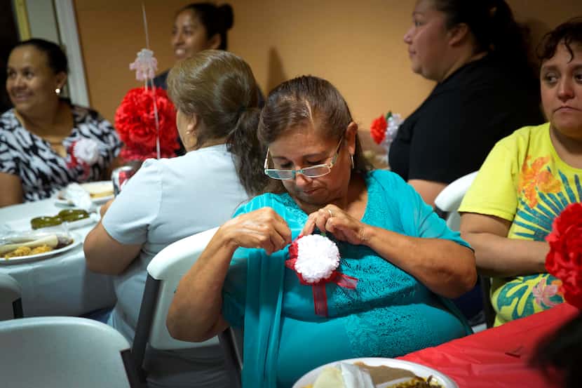 Maria Perez pins a flower to her blouse during the the city's annual Mother's Day Dinner at...