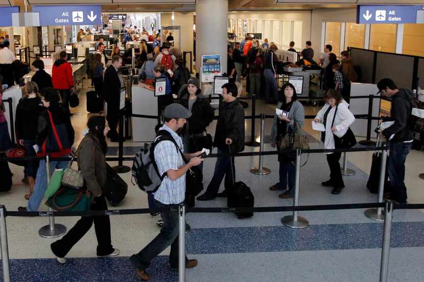 Travelers wait in line to go through security at Terminal D at DFW International Airport.