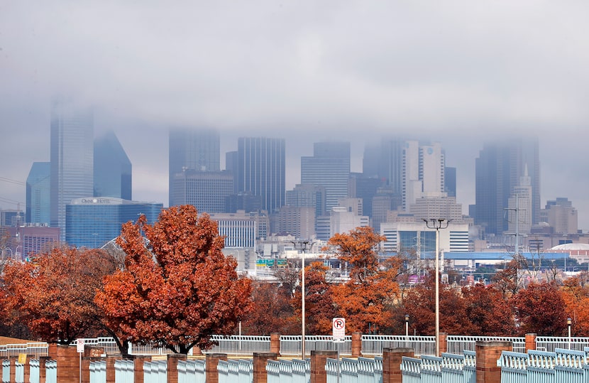 Remnants of morning rain clouds recede from the Dallas skyline on Dec. 11, 2020. Bright red...