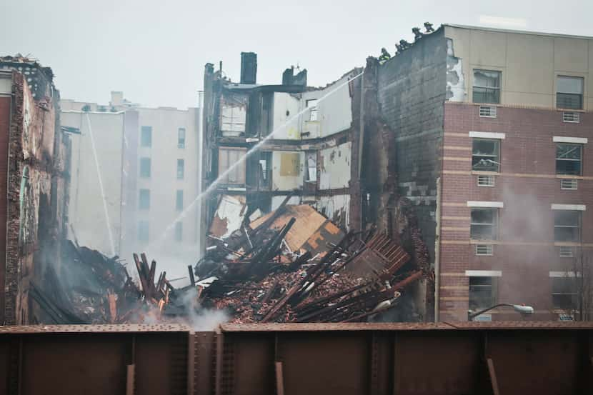 Firefighters spray water on smoldering debris from an explosion in the East Harlem...