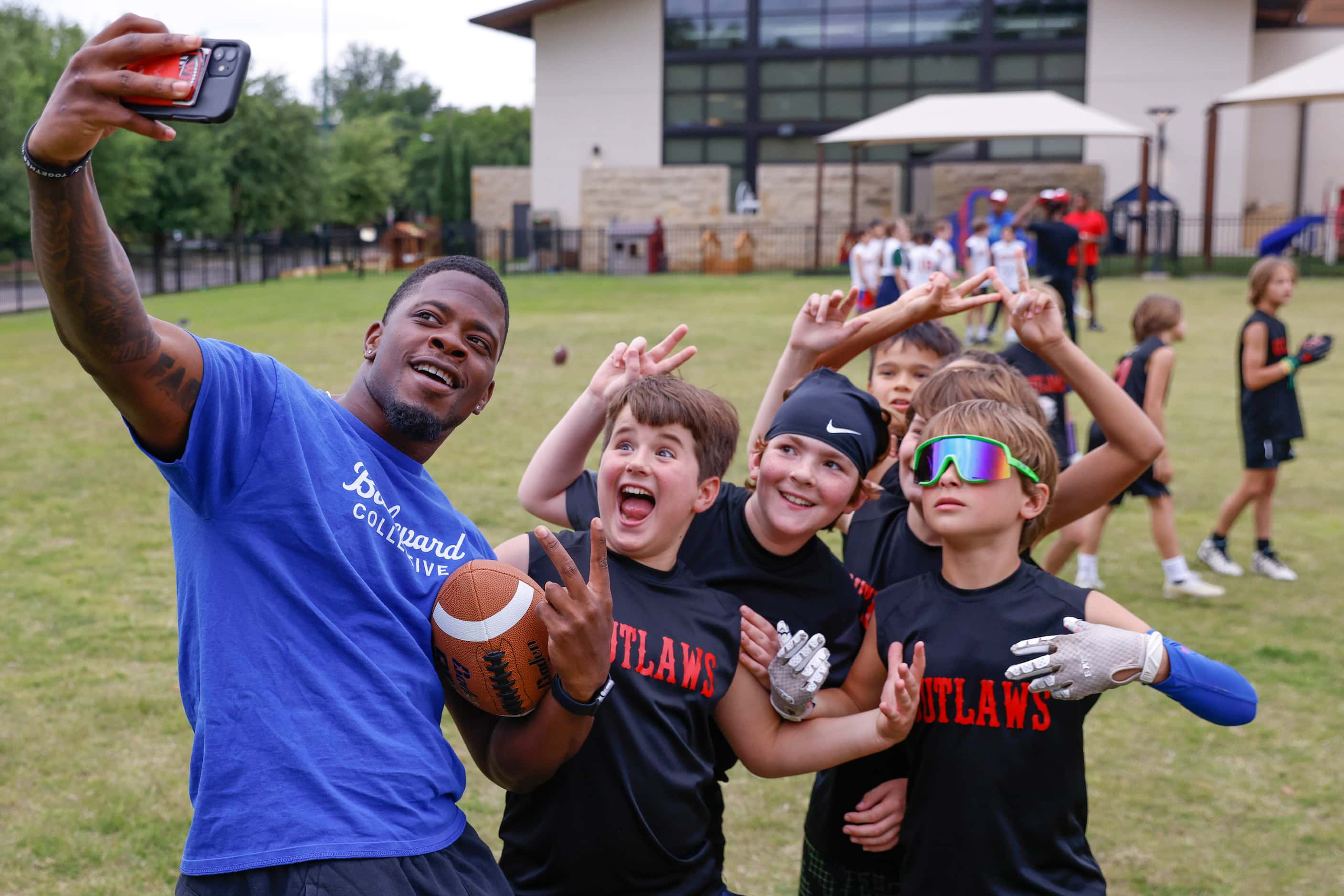 SMU’s Kam Farrar takes a selfie with the kids during a special session of football drills...