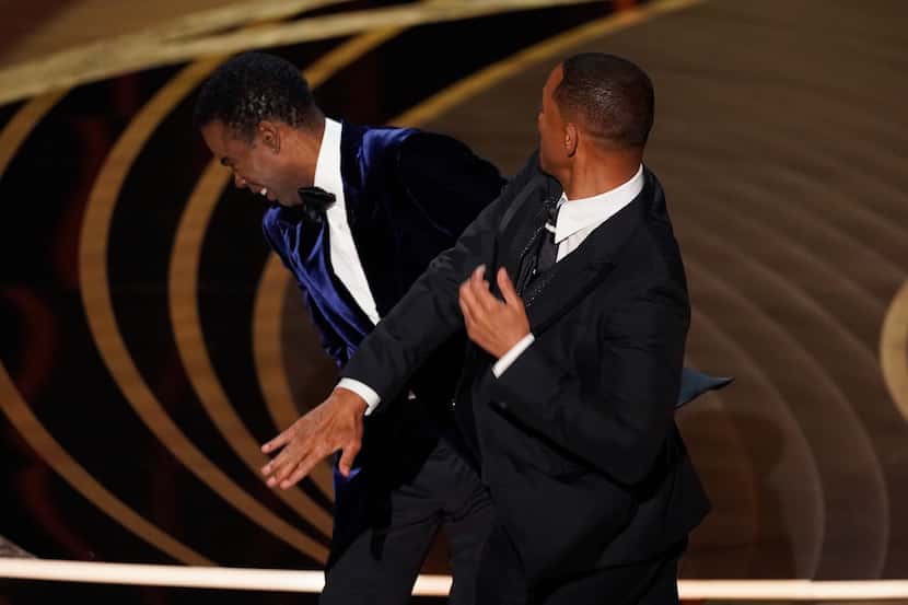 Will Smith, right, hits presenter Chris Rock on stage while presenting the award for best...
