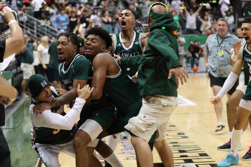 Hawaii guard JoVon McClanahan, second from left, jumps into the crowd with teammates after...