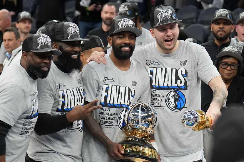 Dallas Mavericks guard Kyrie Irving holds the championship trophy and guard Luka Doncic...