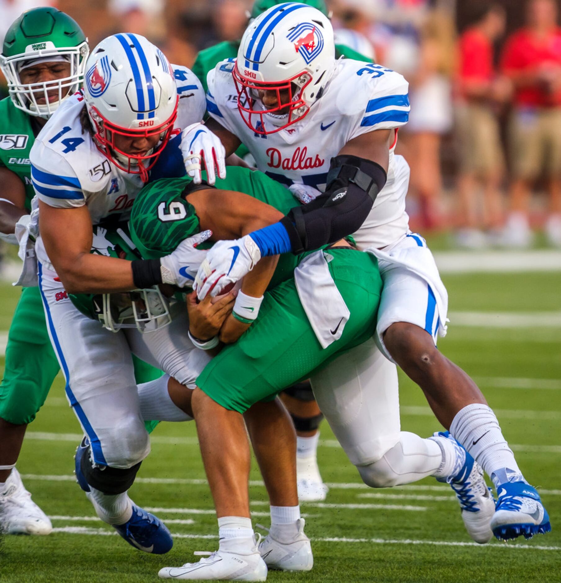 UNT quarterback Mason Fine (6) is sacked by SMU linebacker Richard Moore (14) and defensive...