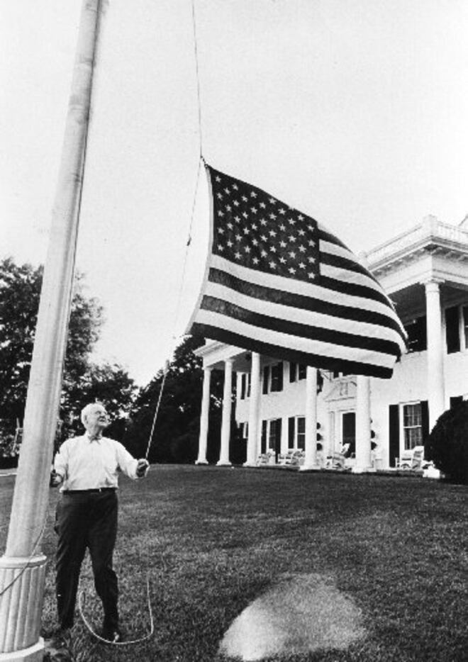H.L. Hunt personally raises and lowers the flag in front of his Dallas home, a replica of...