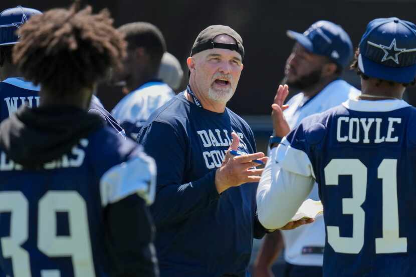 Dallas Cowboys defensive coordinator Dan Quinn talks with players during a training camp...