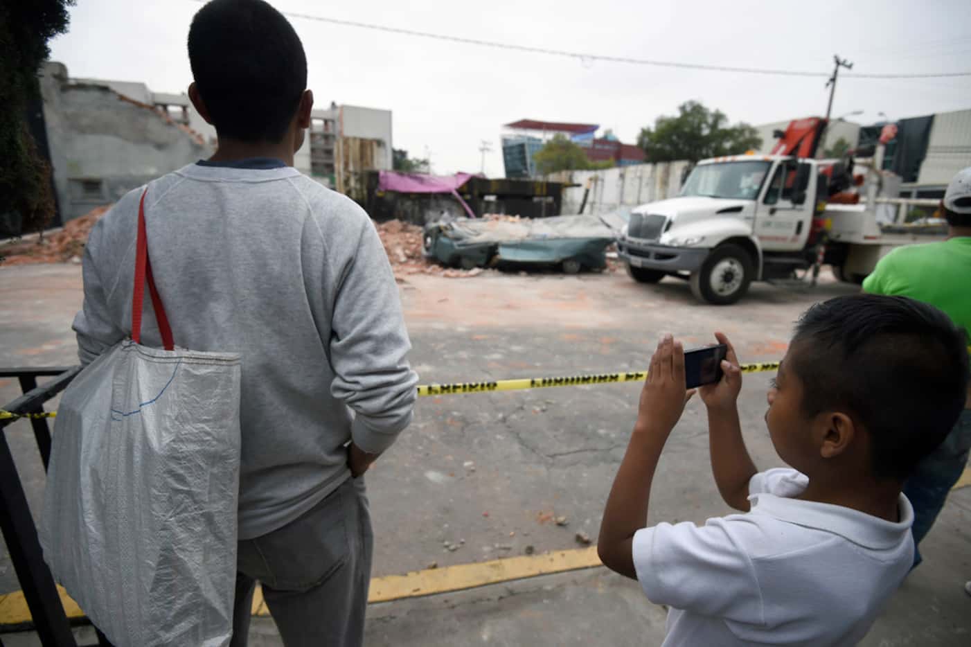 A boy takes pictures of a knocked-down building at the eastern area of Mexico City after a...