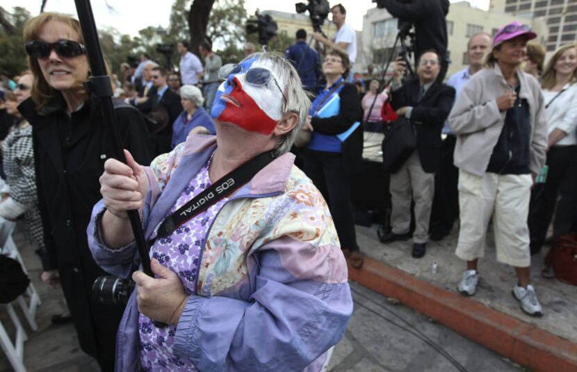 With her face painted like a Texas flag, Lynn Jones of Mesquite hoisted a video camera to...