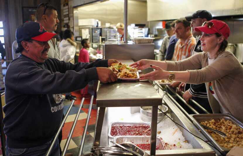 Volunteer Tanya Ragan , right, serves a free Thanksgiving Day meal to Pablo Guzman, left, of...