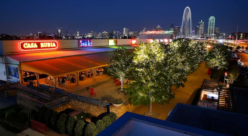 The Margaret Hunt Hill Bridge rises above the Dallas skyline and Trinity Groves restaurant...