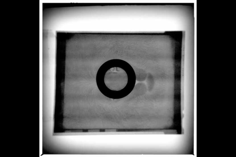 A magnifying loupe sits on a 4x5 negative on a light table.