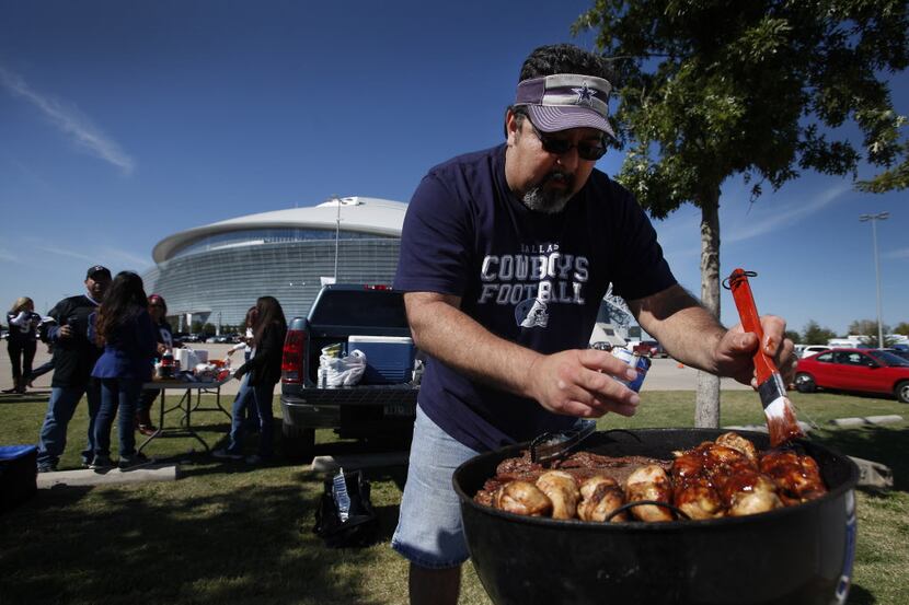 Mike Rico from San Antonio prepares chicken while grilling during tailgating prior to the...