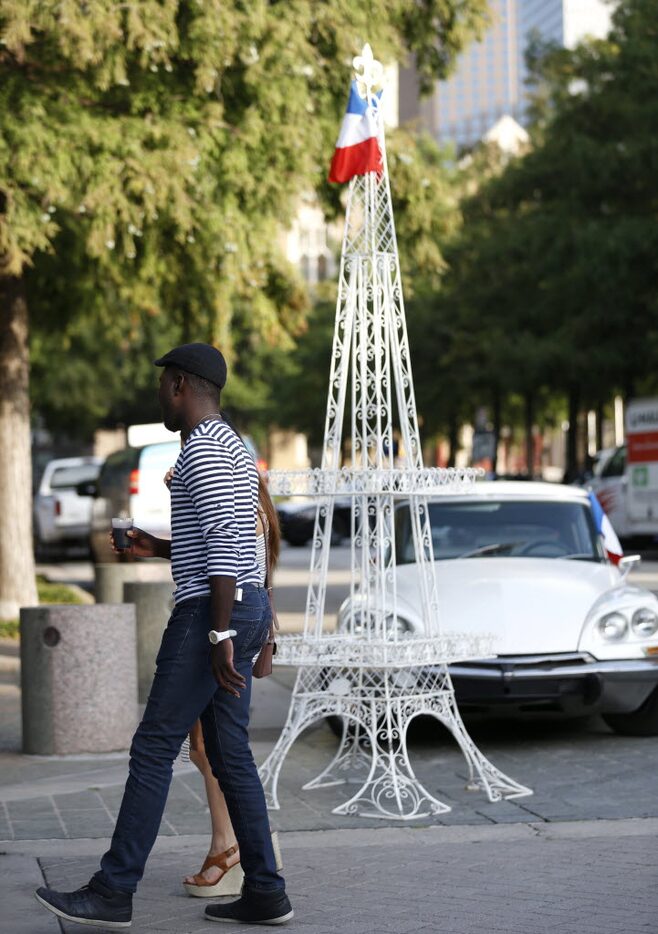 Attendees walk past an Eiffel Tower at Bastille Day in the Arts District in Dallas on...