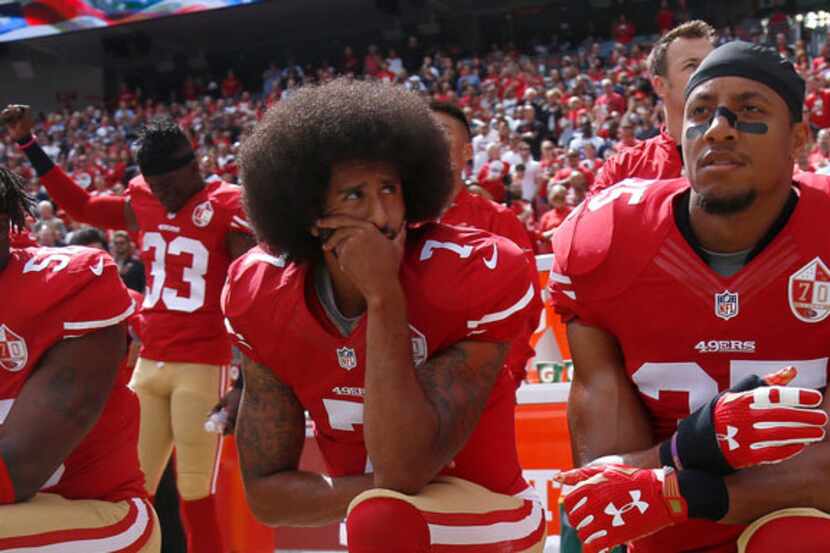 Colin Kaepernick (center) kneels with San Francisco 49ers teammates Eli Harold (left) and...