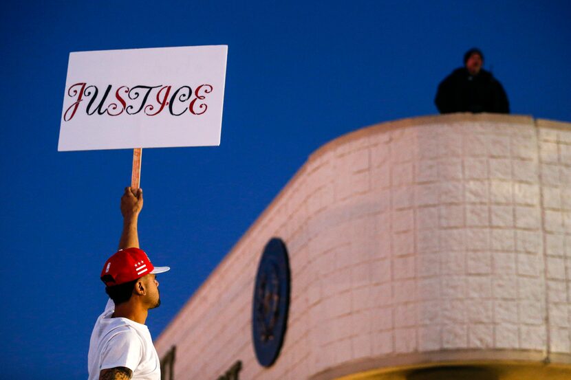 Roof top police watch as demonstrators gather at the Hunt County Sheriff's Department in...