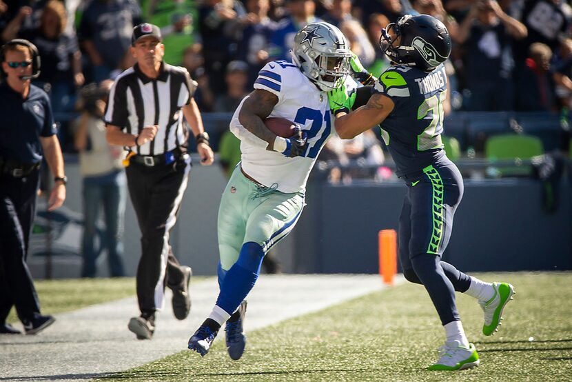 Dallas Cowboys running back Ezekiel Elliott (21) fights off Seattle Seahawks defensive back...