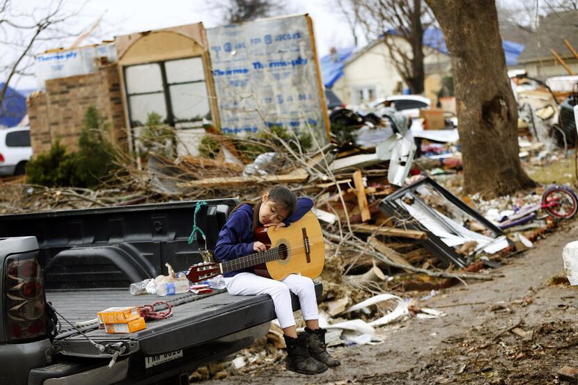 Natalie Rojas, 8, strums a guitar found in the bedroom of her tornado-damaged home on...