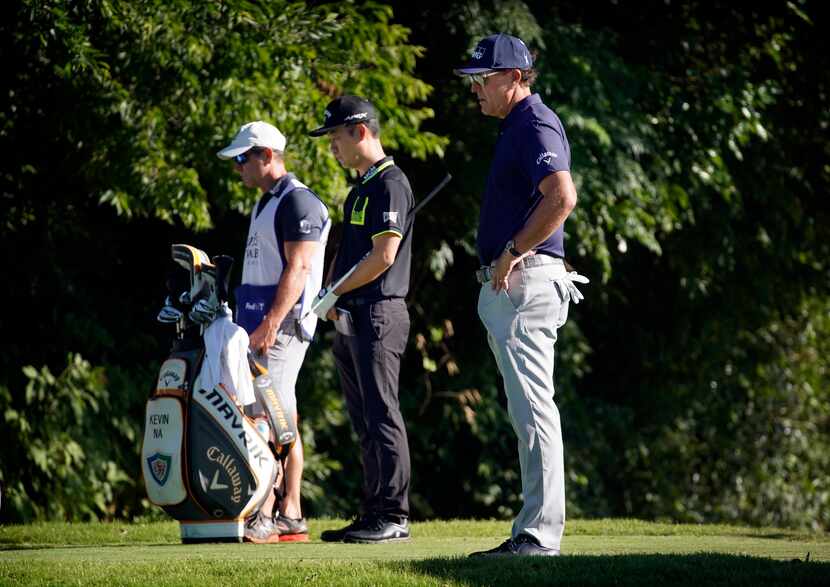 PGA golfers Phil Mickelson (right) and Kevin Na (second from right) observe a minute of...