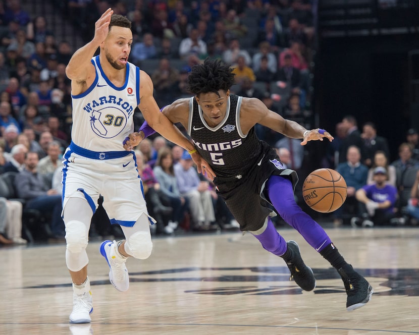 The Sacramento Kings' De'Aaron Fox (5) drives to the basket against the Golden State...