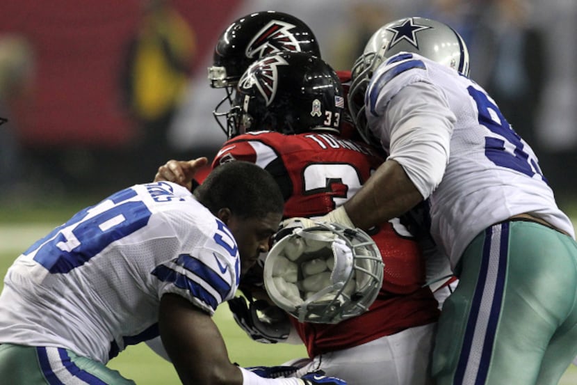 Dallas Cowboys linebacker Ernie Sims (59) looses his helmet while tackling Atlanta Falcons...
