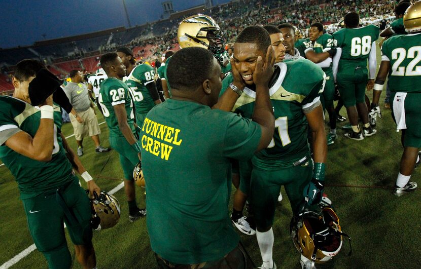 A man holds the face of DeSoto player Nick Orr (31), as other players seem to mill about...