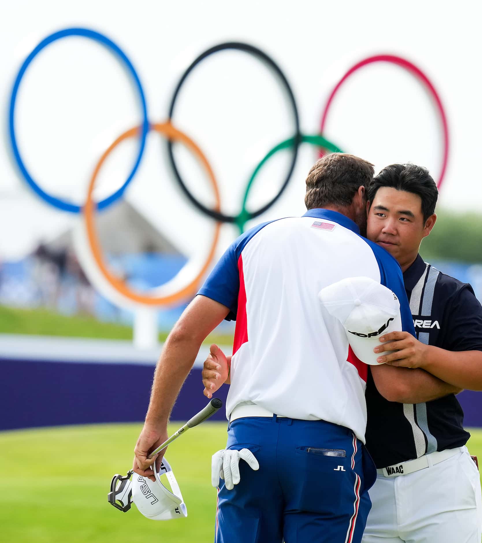 Scottie Scheffler of the United States hugs Tom Kim of South Korea (facing) on the 18th...