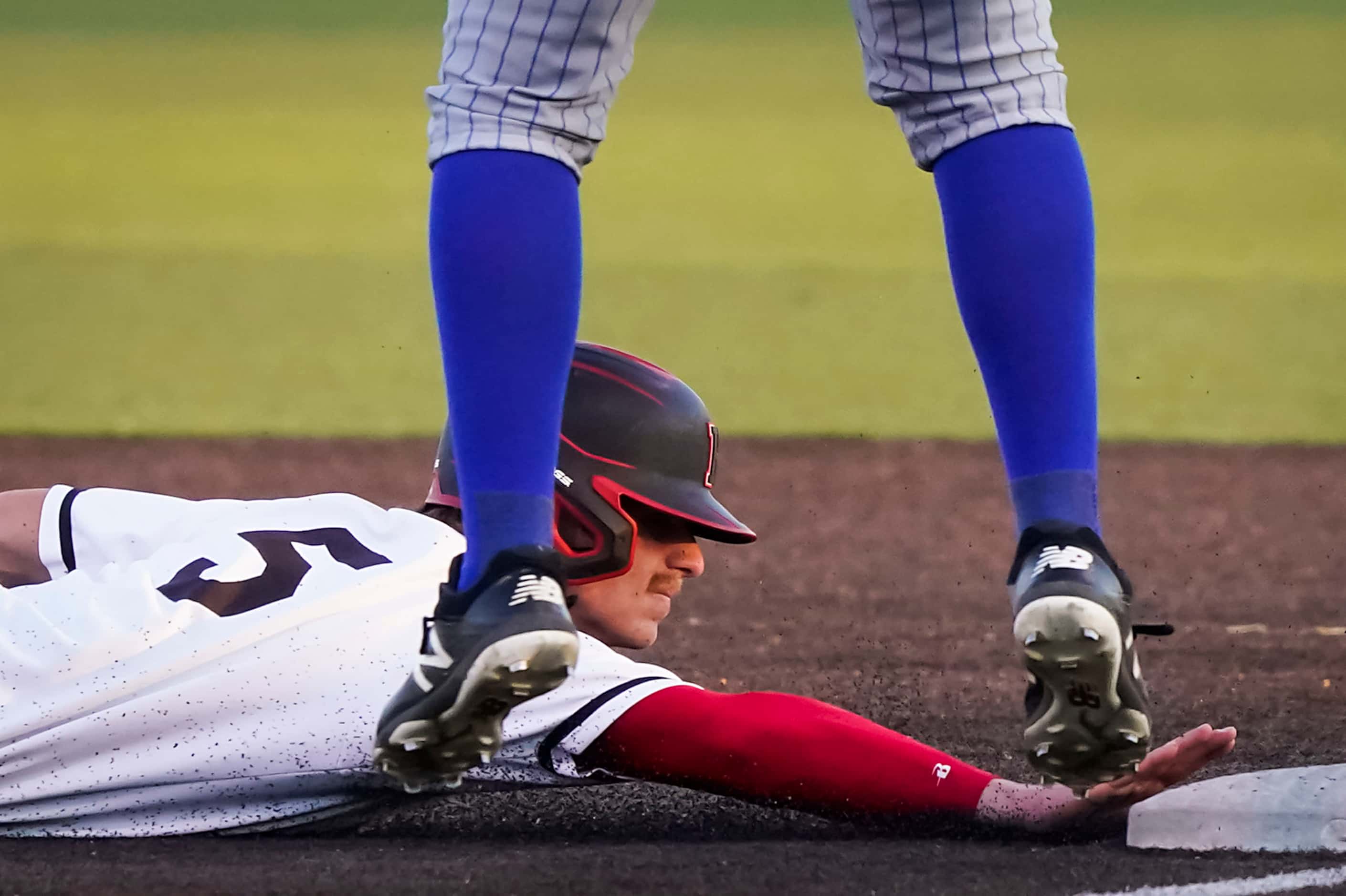 Rockwall-Heath shortstop Karson Krowka (5) dives back to first on a pickoff play during a...