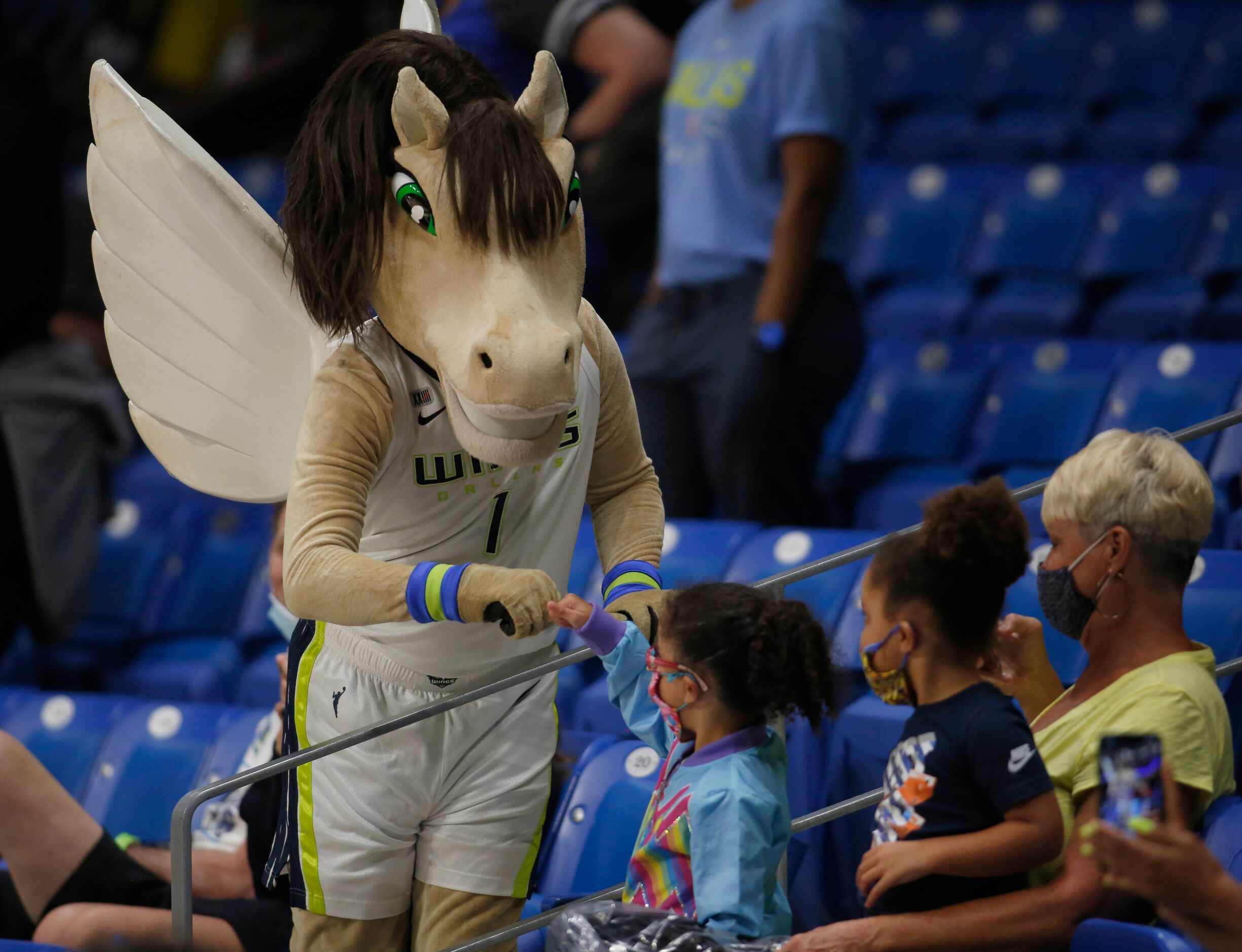 The Dallas Wings mascot shares a "fist bump" with a young fan in the crowd during second...