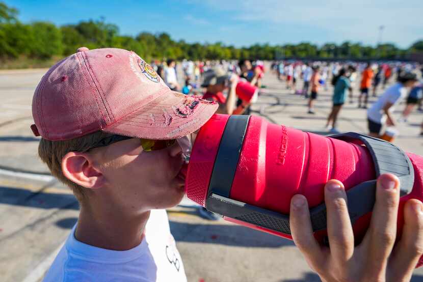 Zach Ebert drinks water as members of the Coppell marching band pause  during a morning...