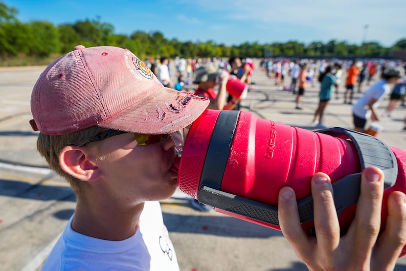 Zach Ebert drinks water as members of the Coppell marching band pause  during a morning...