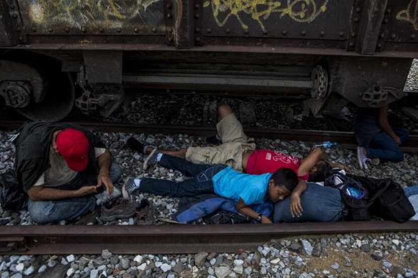 
A Honduran man and his son sleep by the tracks in Tierra Blanca, Mexico, while waiting for...