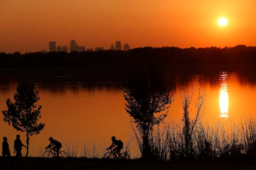 Cyclists ride on the path at White Rock Lake near the Test Pavilion at the Dallas Arboretum....